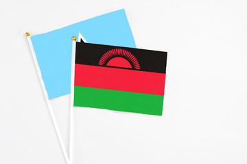 Malawi and Saint Lucia stick flags on white background. High quality fabric, miniature national flag. Peaceful global concept.White floor for copy space.