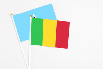 Fototapeta premium Mali and Saint Lucia stick flags on white background. High quality fabric, miniature national flag. Peaceful global concept.White floor for copy space.