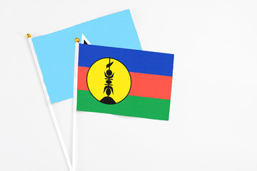 New Caledonia and Saint Lucia stick flags on white background. High quality fabric, miniature national flag. Peaceful global concept.White floor for copy space.