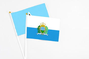 San Marino and Saint Lucia stick flags on white background. High quality fabric, miniature national flag. Peaceful global concept.White floor for copy space.