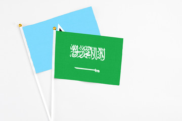 Saudi Arabia and Saint Lucia stick flags on white background. High quality fabric, miniature national flag. Peaceful global concept.White floor for copy space.