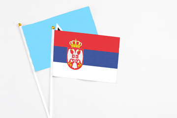 Serbia and Saint Lucia stick flags on white background. High quality fabric, miniature national flag. Peaceful global concept.White floor for copy space.