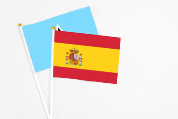 Fototapeta premium Spain and Saint Lucia stick flags on white background. High quality fabric, miniature national flag. Peaceful global concept.White floor for copy space.