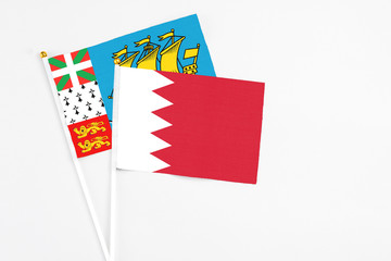 Bahrain and Saint Pierre And Miquelon stick flags on white background. High quality fabric, miniature national flag. Peaceful global concept.White floor for copy space.