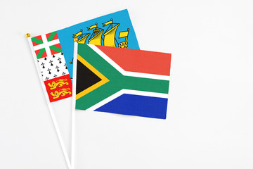South Africa and Saint Pierre And Miquelon stick flags on white background. High quality fabric, miniature national flag. Peaceful global concept.White floor for copy space.