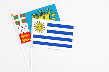 Uruguay and Saint Pierre And Miquelon stick flags on white background. High quality fabric, miniature national flag. Peaceful global concept.White floor for copy space.