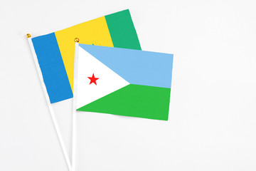 Djibouti and Saint Vincent And The Grenadines stick flags on white background. High quality fabric, miniature national flag. Peaceful global concept.White floor for copy space.