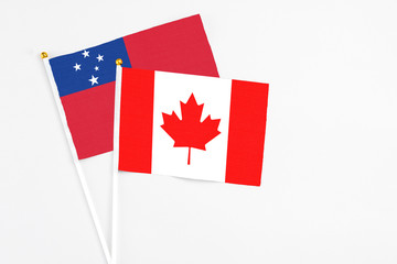Canada and Samoa stick flags on white background. High quality fabric, miniature national flag. Peaceful global concept.White floor for copy space.