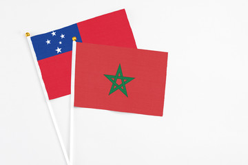 Morocco and Samoa stick flags on white background. High quality fabric, miniature national flag. Peaceful global concept.White floor for copy space.