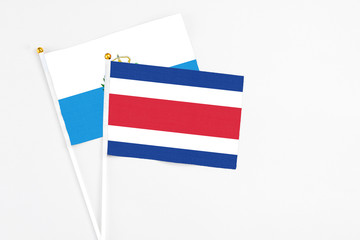 Costa Rica and San Marino stick flags on white background. High quality fabric, miniature national flag. Peaceful global concept.White floor for copy space.