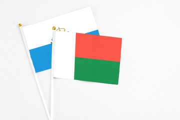 Madagascar and San Marino stick flags on white background. High quality fabric, miniature national flag. Peaceful global concept.White floor for copy space.