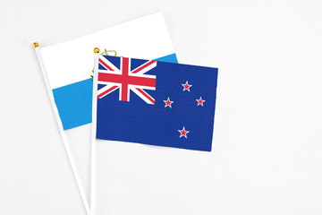 Fototapeta premium New Zealand and San Marino stick flags on white background. High quality fabric, miniature national flag. Peaceful global concept.White floor for copy space.