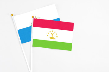 Tajikistan and San Marino stick flags on white background. High quality fabric, miniature national flag. Peaceful global concept.White floor for copy space.