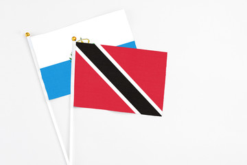 Trinidad And Tobago and San Marino stick flags on white background. High quality fabric, miniature national flag. Peaceful global concept.White floor for copy space.