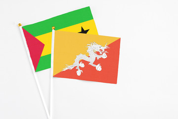 Bhutan and Sao Tome And Principe stick flags on white background. High quality fabric, miniature national flag. Peaceful global concept.White floor for copy space.