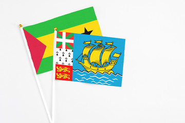 Saint Pierre And Miquelon and Sao Tome And Principe stick flags on white background. High quality fabric, miniature national flag. Peaceful global concept.White floor for copy space.