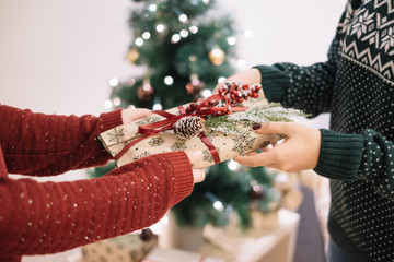 Mother giving present in front of Christmas tree
