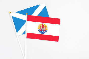 French Polynesia and Scotland stick flags on white background. High quality fabric, miniature national flag. Peaceful global concept.White floor for copy space.