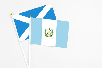 Guatemala and Scotland stick flags on white background. High quality fabric, miniature national flag. Peaceful global concept.White floor for copy space.