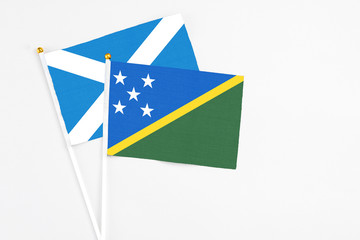 Solomon Islands and Scotland stick flags on white background. High quality fabric, miniature national flag. Peaceful global concept.White floor for copy space.