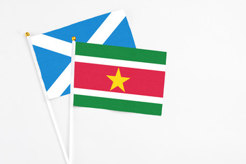 Obraz premium Suriname and Scotland stick flags on white background. High quality fabric, miniature national flag. Peaceful global concept.White floor for copy space.