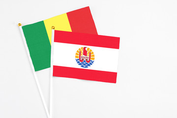 French Polynesia and Senegal stick flags on white background. High quality fabric, miniature national flag. Peaceful global concept.White floor for copy space.