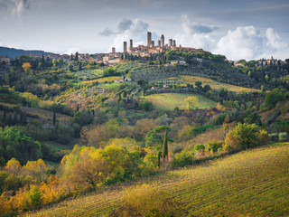 Fototapeta na wymiar hills in sun lights with view to old city San Gimignano with towers in Tuscany in Italy