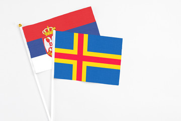 Aland Islands and Serbia stick flags on white background. High quality fabric, miniature national flag. Peaceful global concept.White floor for copy space.