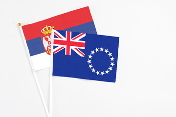 Fototapeta premium Cook Islands and Serbia stick flags on white background. High quality fabric, miniature national flag. Peaceful global concept.White floor for copy space.