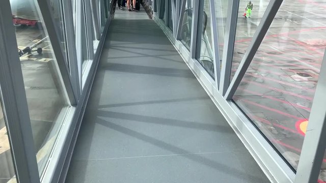 POV of passenger walking on jet bridge, jetway or airgate. People goes into the passenger boarding bridge to the airplane. Airport terminal gate to an airplane. Tourists ready for fly.  