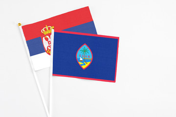 Guam and Serbia stick flags on white background. High quality fabric, miniature national flag. Peaceful global concept.White floor for copy space.