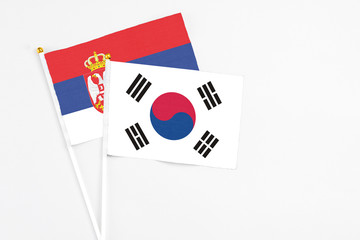 South Korea and Serbia stick flags on white background. High quality fabric, miniature national flag. Peaceful global concept.White floor for copy space.