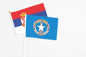 Northern Mariana Islands and Serbia stick flags on white background. High quality fabric, miniature national flag. Peaceful global concept.White floor for copy space.