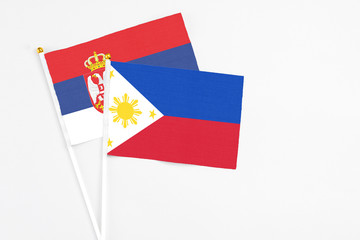 Philippines and Serbia stick flags on white background. High quality fabric, miniature national flag. Peaceful global concept.White floor for copy space.