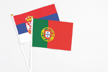 Portugal and Serbia stick flags on white background. High quality fabric, miniature national flag. Peaceful global concept.White floor for copy space.