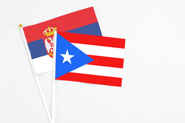 Puerto Rico and Serbia stick flags on white background. High quality fabric, miniature national flag. Peaceful global concept.White floor for copy space.