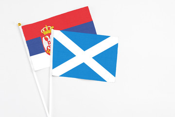 Scotland and Serbia stick flags on white background. High quality fabric, miniature national flag. Peaceful global concept.White floor for copy space.