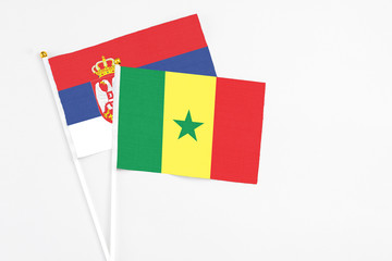 Senegal and Serbia stick flags on white background. High quality fabric, miniature national flag. Peaceful global concept.White floor for copy space.