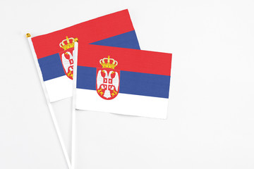 Serbia and Serbia stick flags on white background. High quality fabric, miniature national flag. Peaceful global concept.White floor for copy space.