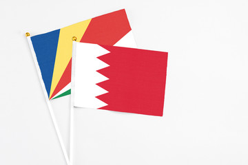 Bahrain and Seychelles stick flags on white background. High quality fabric, miniature national flag. Peaceful global concept.White floor for copy space.v