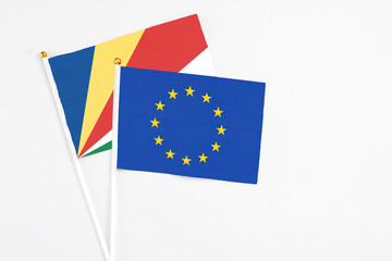 European Union and Seychelles stick flags on white background. High quality fabric, miniature national flag. Peaceful global concept.White floor for copy space.v