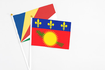 Guadeloupe and Seychelles stick flags on white background. High quality fabric, miniature national flag. Peaceful global concept.White floor for copy space.v