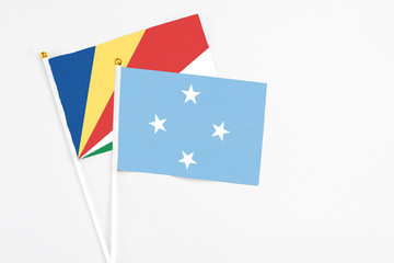 Micronesia and Seychelles stick flags on white background. High quality fabric, miniature national flag. Peaceful global concept.White floor for copy space.v