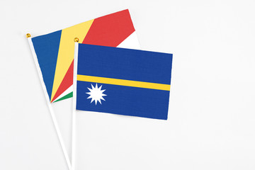 Nauru and Seychelles stick flags on white background. High quality fabric, miniature national flag. Peaceful global concept.White floor for copy space.v