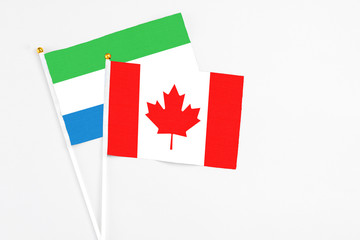 Canada and Sierra Leone stick flags on white background. High quality fabric, miniature national flag. Peaceful global concept.White floor for copy space.