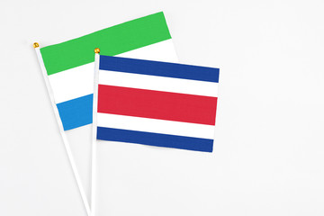 Costa Rica and Sierra Leone stick flags on white background. High quality fabric, miniature national flag. Peaceful global concept.White floor for copy space.
