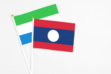 Laos and Sierra Leone stick flags on white background. High quality fabric, miniature national flag. Peaceful global concept.White floor for copy space.