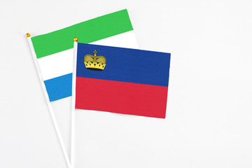 Liechtenstein and Sierra Leone stick flags on white background. High quality fabric, miniature national flag. Peaceful global concept.White floor for copy space.