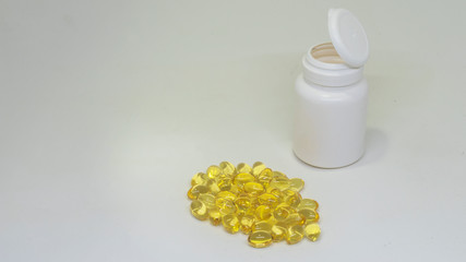 White jar of pills and fish oil pills on white background. White medical containers.