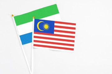 Malaysia and Sierra Leone stick flags on white background. High quality fabric, miniature national flag. Peaceful global concept.White floor for copy space.